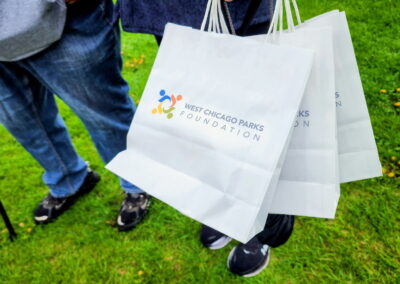a hand is holding several bags labeled with the west chicago parks foundation logo