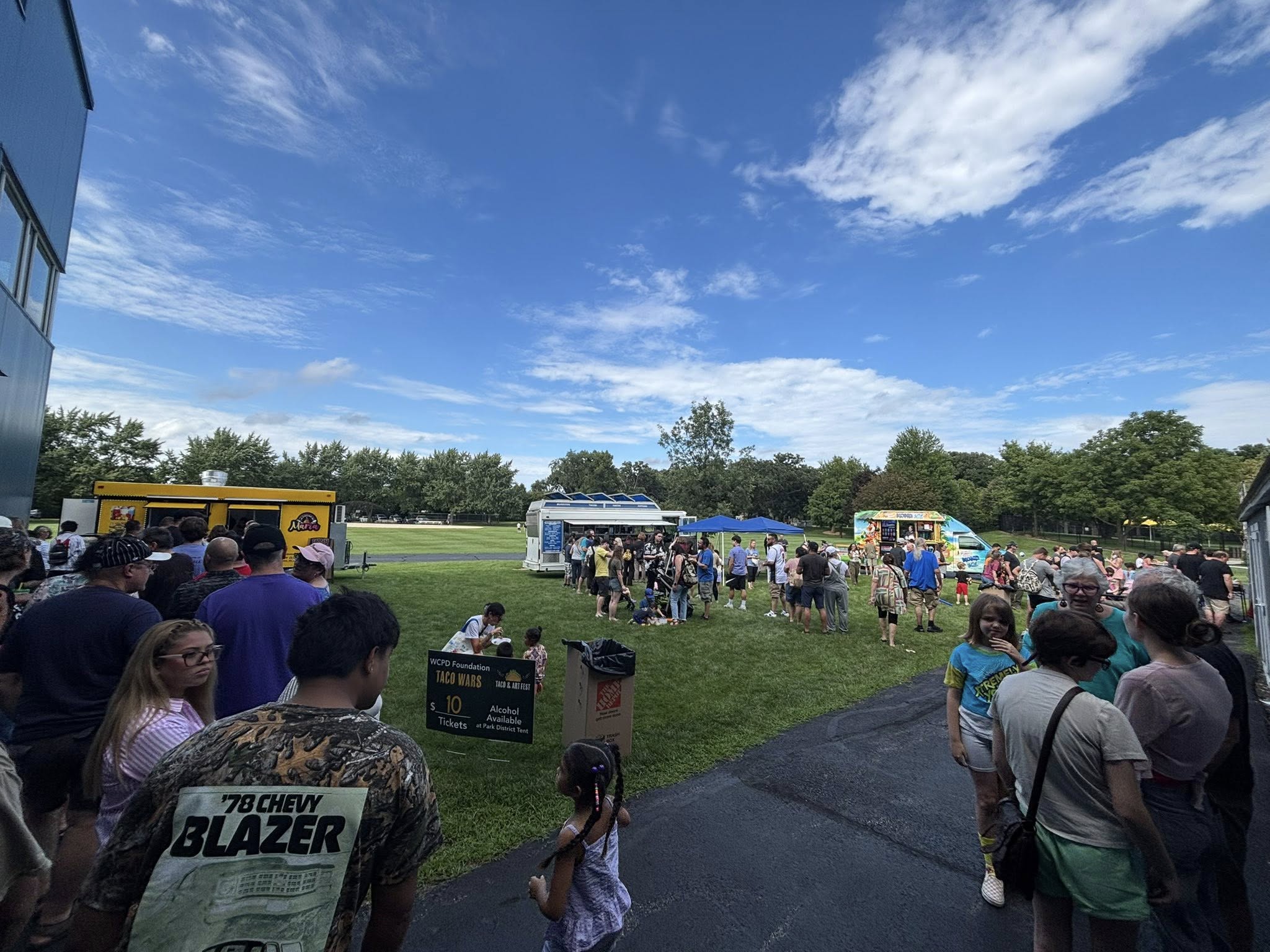 tw3 Taco trucks circled outside on a beautiful sunny day while people wait in line to order food
