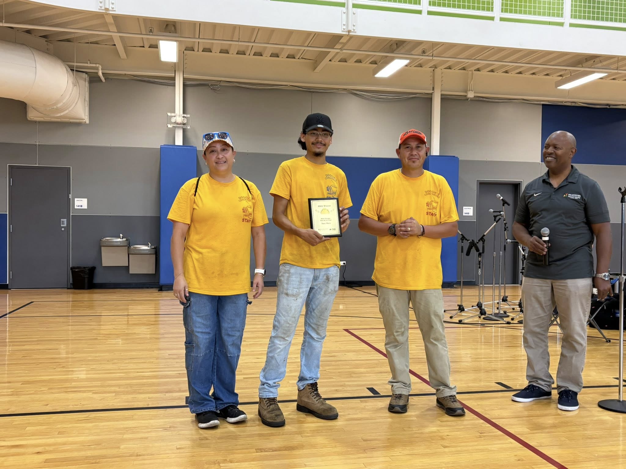 tw6 Three workers from the West Chicago shop 'La India' hold up a plaque declaring them the winners of the taco wars 2025 while the foundation president looks on